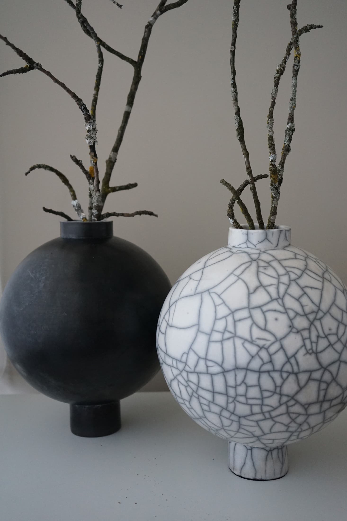 Weisse Kugelvase mit Zweigen