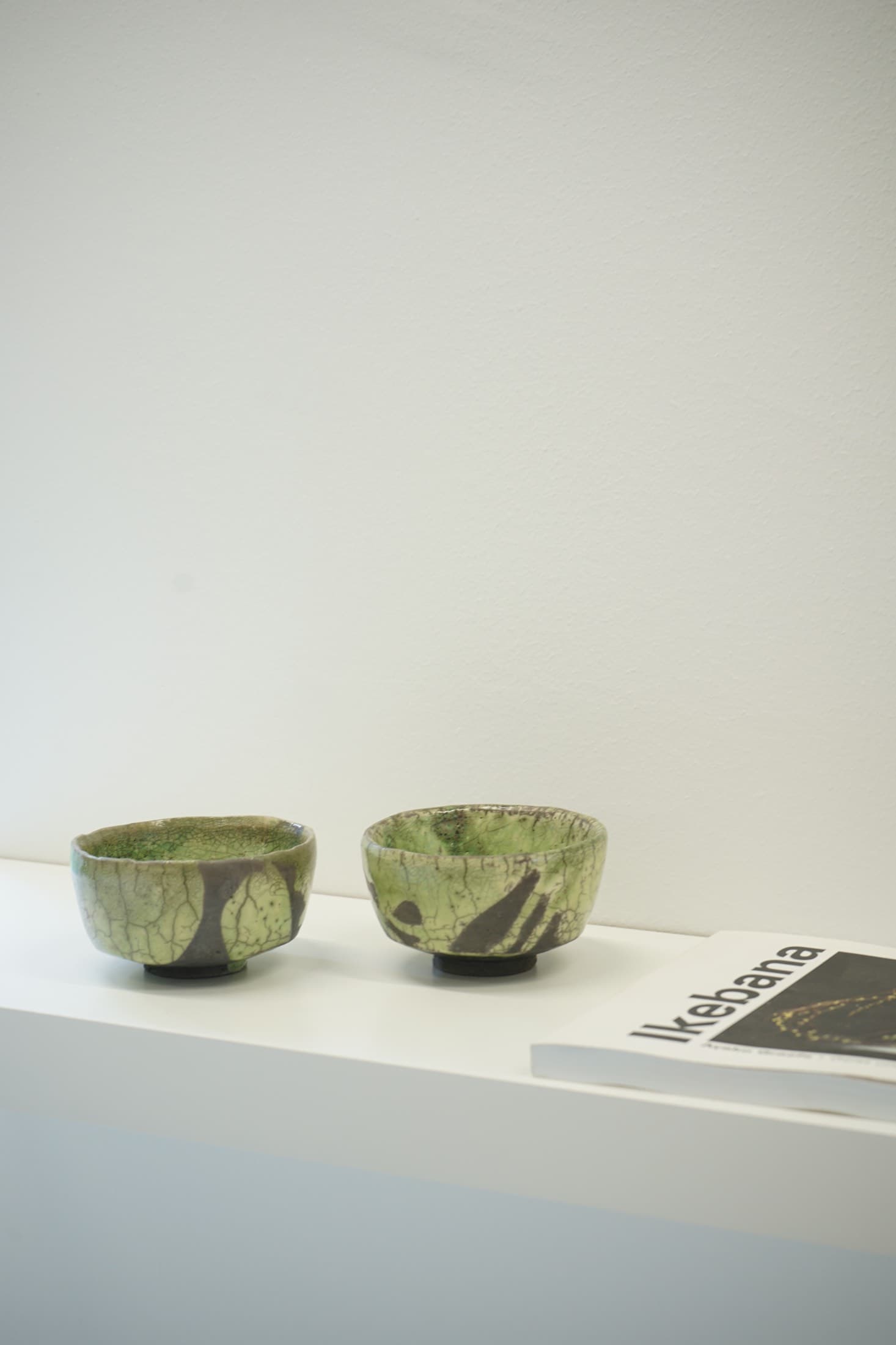 Two tea bowls in green with a dark brushstroke pattern