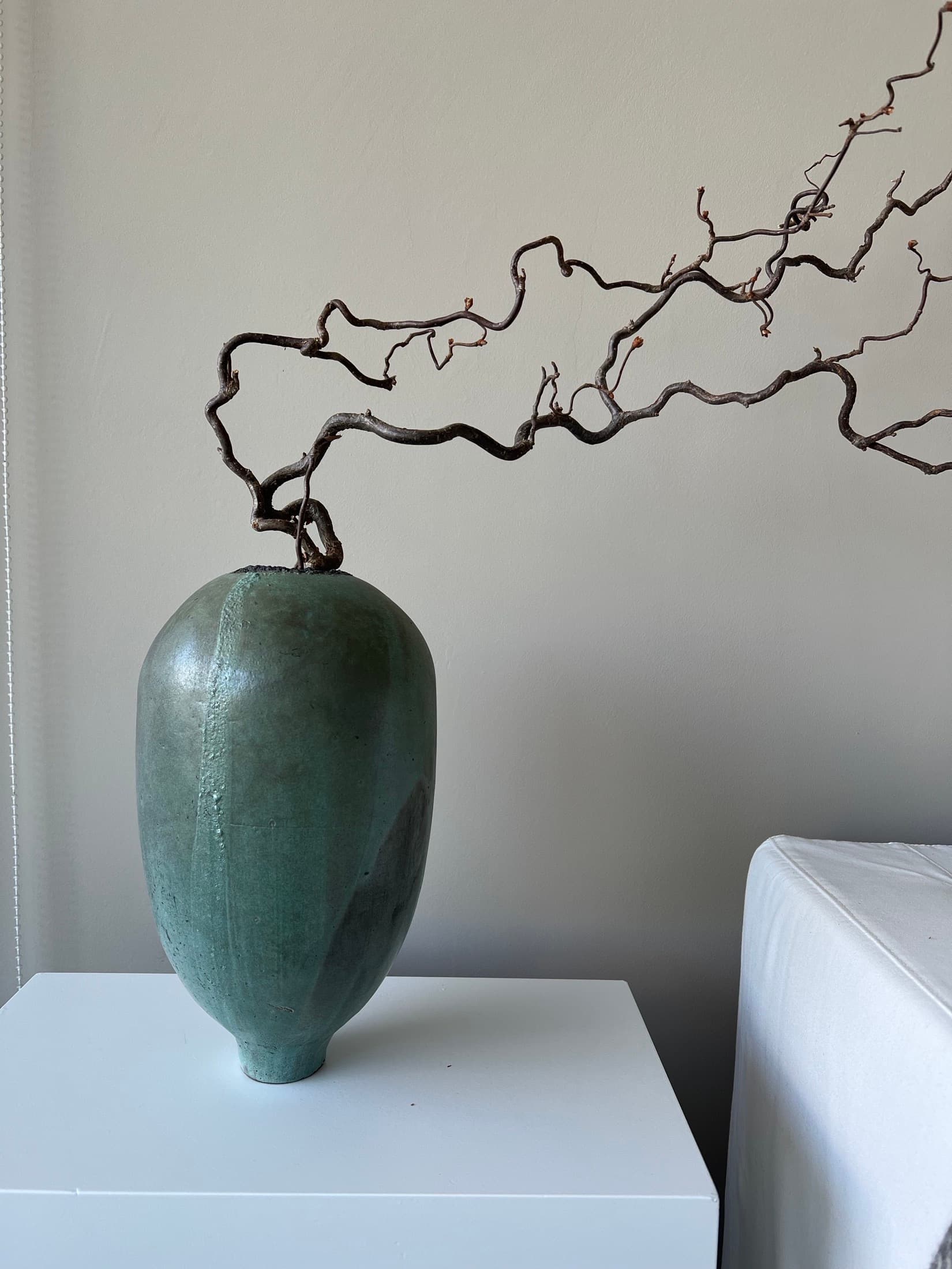 Egg-shaped vase in green with a gnarled branch