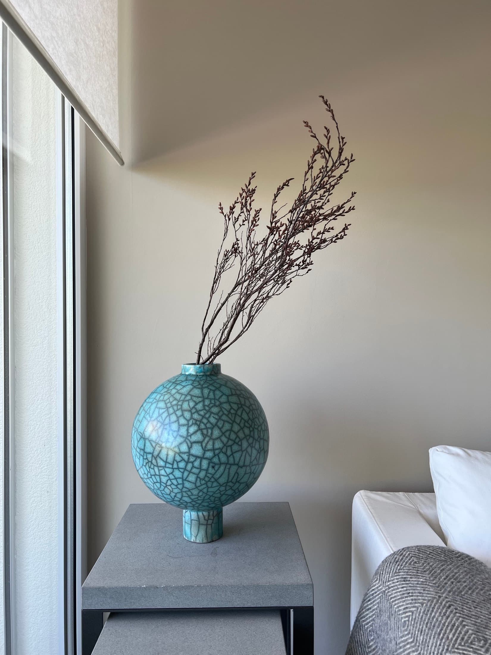 Round vase with a turquoise crackle glaze and a branch