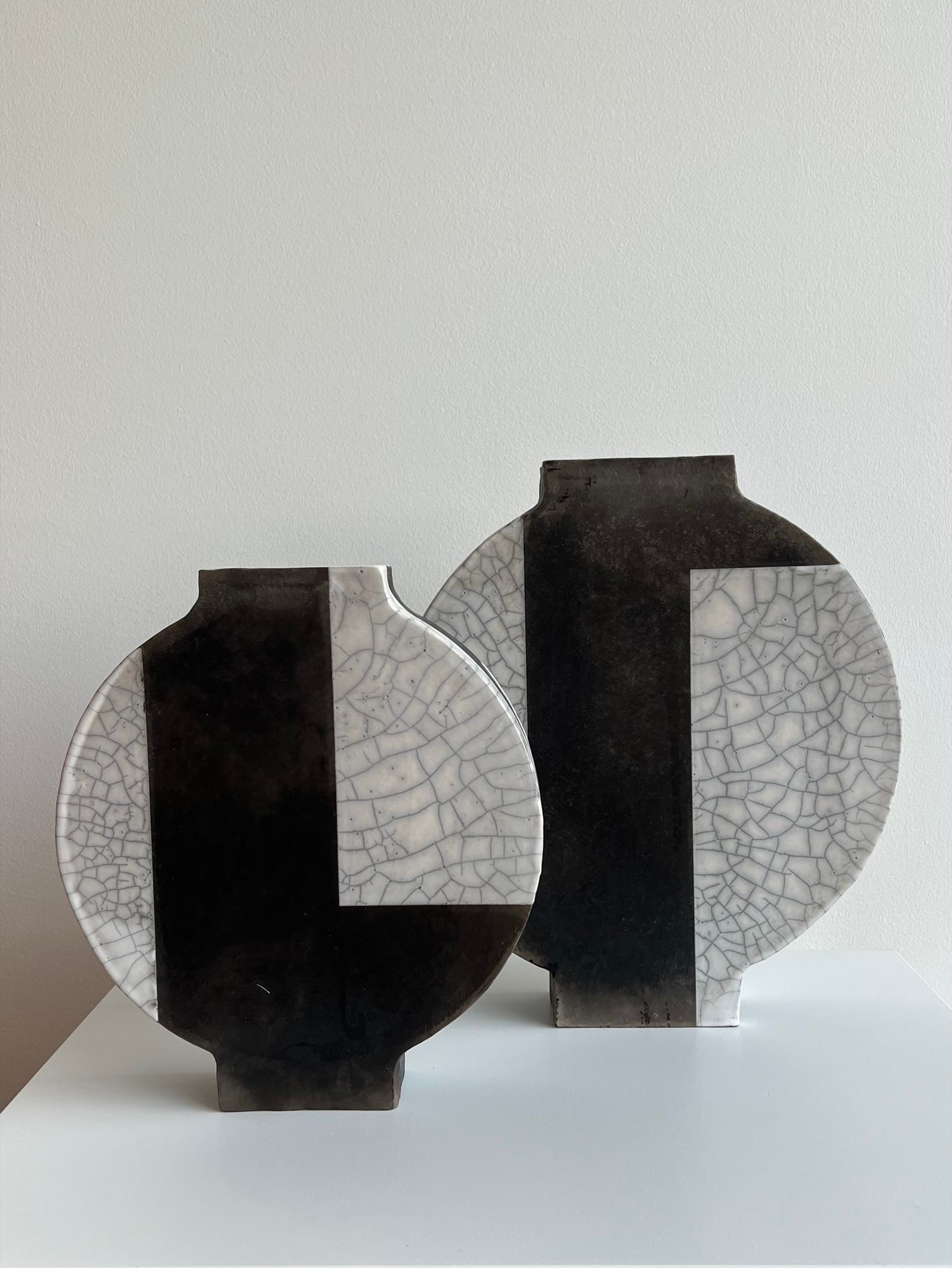 Two disc-shaped vases in black and white with crackle-glazed panels