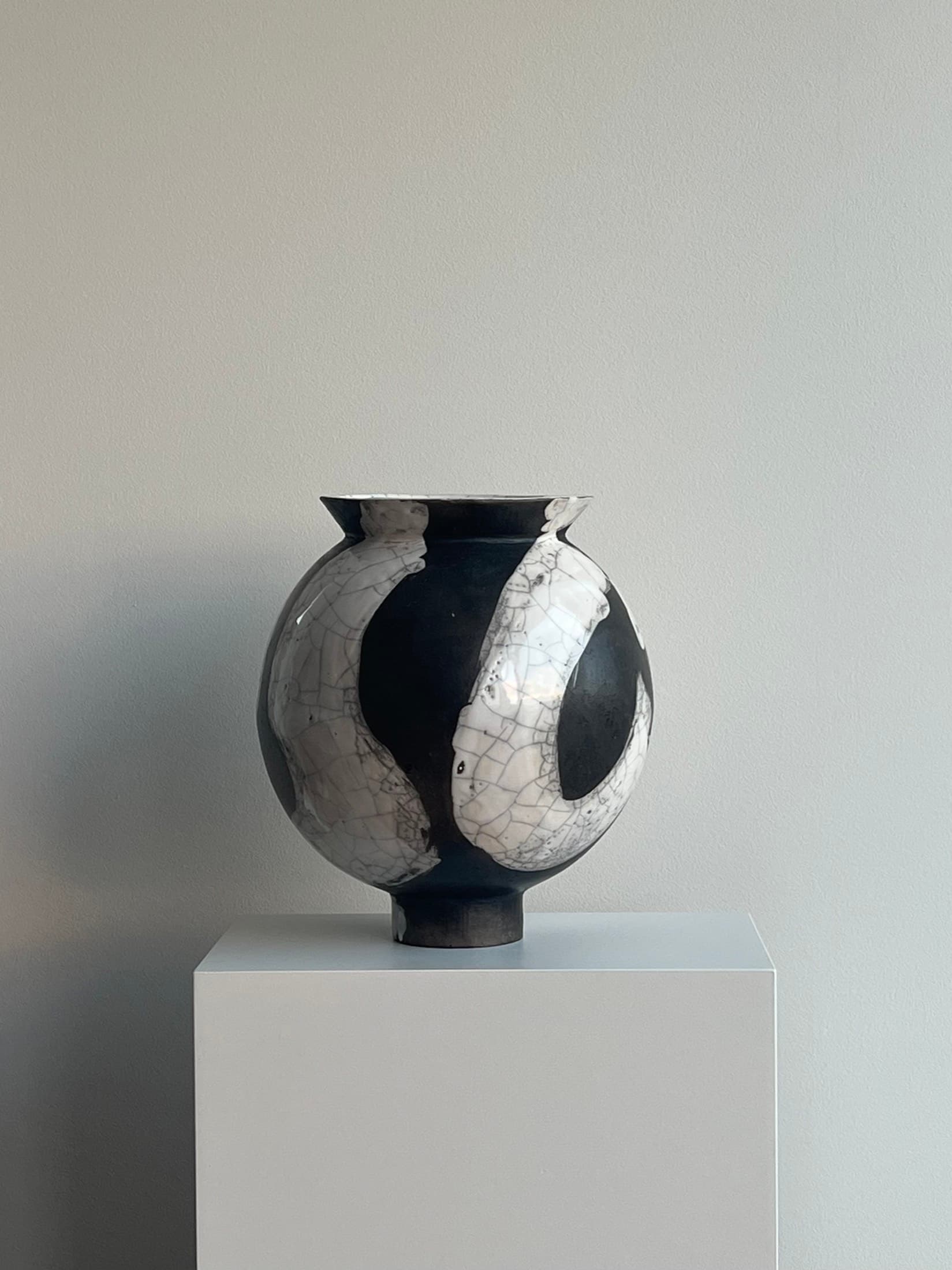 Runde Vase mit schwarz-weissem Craquelé auf einem Sockel